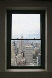 Modern cityscape against sky seen through window