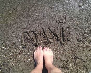 Low section of person standing on sand at beach