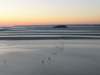 People walking in the low tide at sunset in normandy