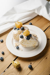 Two pieces of meringue roll with berries on a plate.