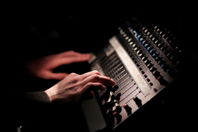 Cropped hands of musician using sound mixer in dark at recording studio