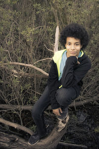 Portrait of teenage boy on fallen tree