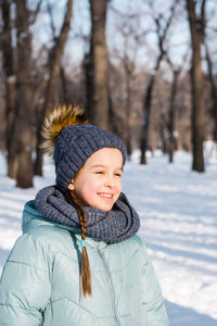 Portrait of a cheerful girl in warm clothes in a winter park on a frosty sunny day. outside walks.