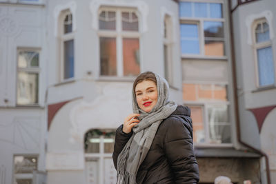 Young woman standing against building
