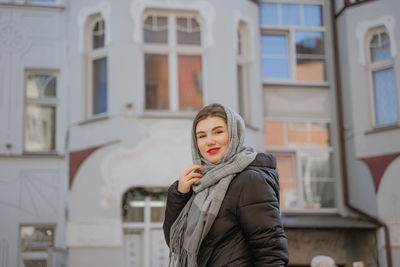 A girl in a scarf and red lips on a walk, smiling looks at the camera, faith forcing to cover her 