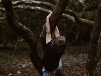 Boy climbing on tree in forest