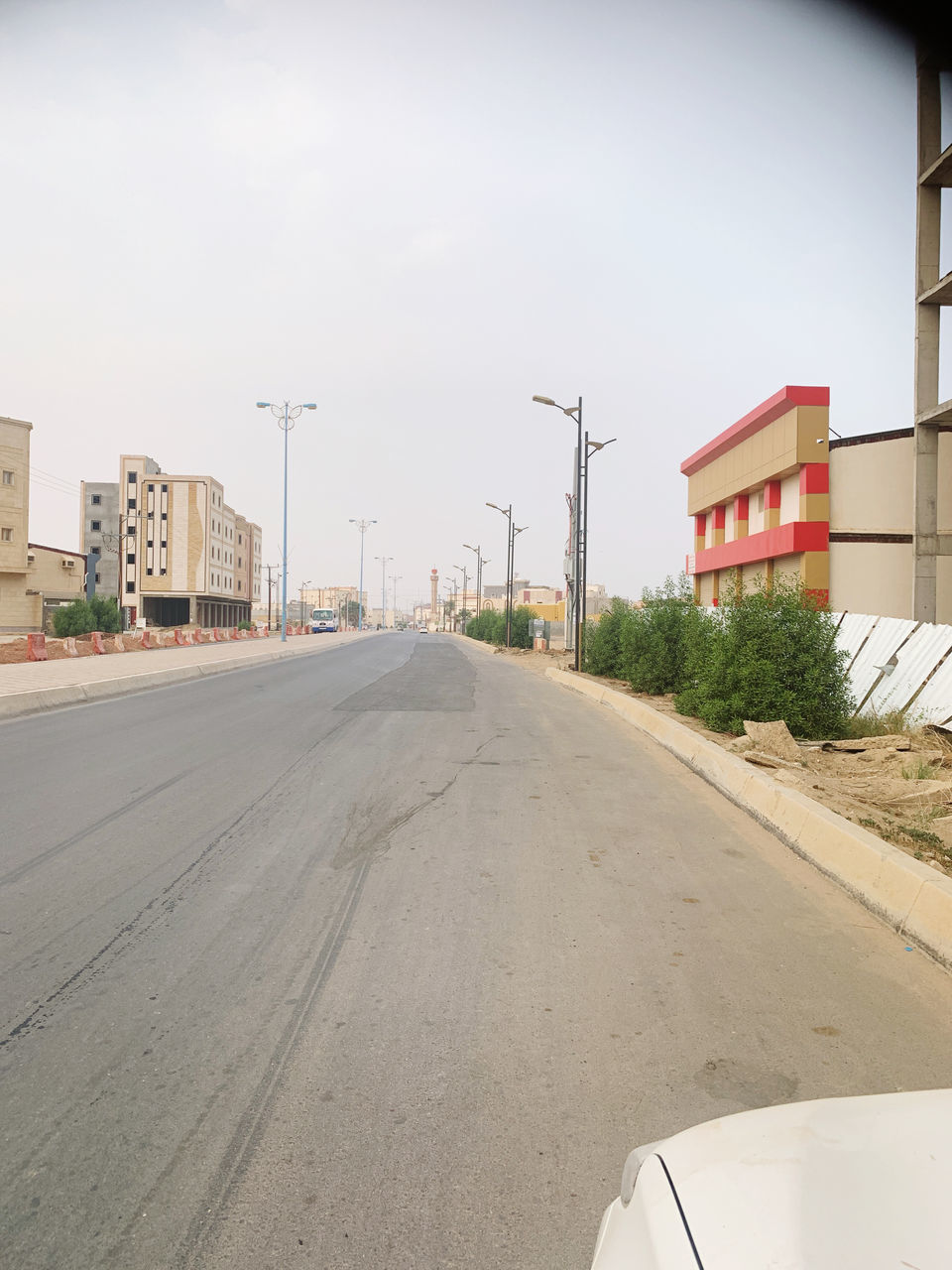 EMPTY ROAD BY BUILDINGS AGAINST SKY