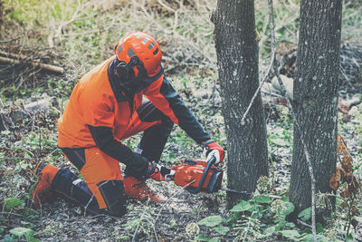 Man holding a chainsaw and cut trees. lumberjack at work. gardener working outdoor in the forest.