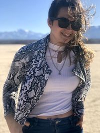 Smiling woman wearing sunglasses standing against sky