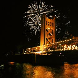 Illuminated suspension bridge over river at night