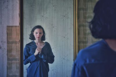 Thoughtful woman standing by mirror at home