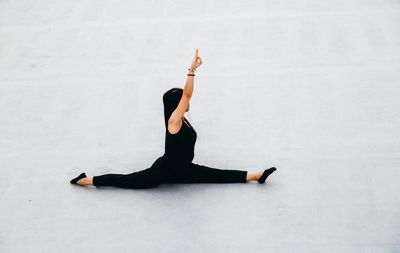 Full length of woman doing yoga against white background