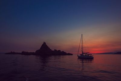 Silhouette sailboat sailing on sea against sky during sunset