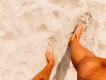 Low section of woman relaxing on sand at beach