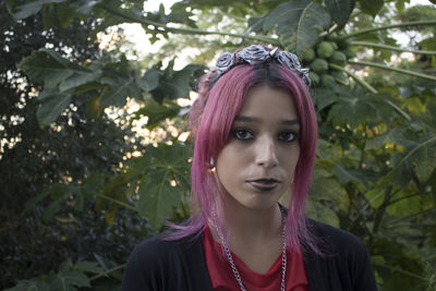 Portrait of woman pink dyed hair standing against plants