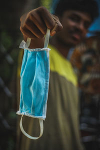 Close-up of man holding bottle against blue background