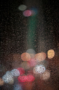 Close-up of wet glass window against black background