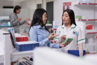 Portrait of female friends using digital tablet while sitting at clinic