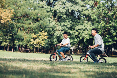 Boy riding bicycle with father on grass