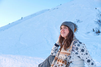 Full length of smiling woman standing on snowcapped mountain