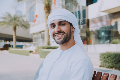 Young man sitting against building in city