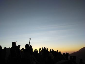 Silhouette people against sky during sunrise