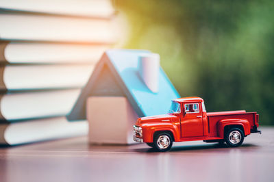 Close-up of toy car and model home with on stacked books on table