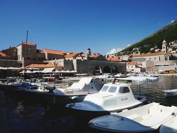 Sailboats moored at harbor against blue sky