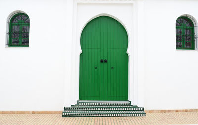 Closed traditional morrocan exterior green door with two windows 