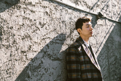 Young man looking away against wall