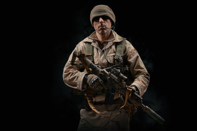 Man holding rifle against black background