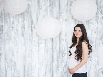 Portrait of woman standing against white wall