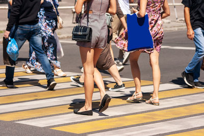 Low section of people walking on road in city