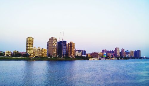 City at waterfront against clear sky