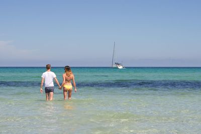Rear view of women on beach against sky
