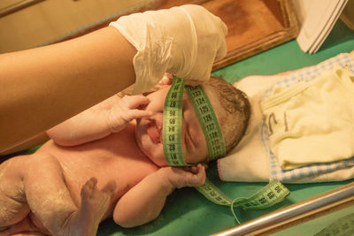 Cropped hand of doctor measuring baby girl with tape