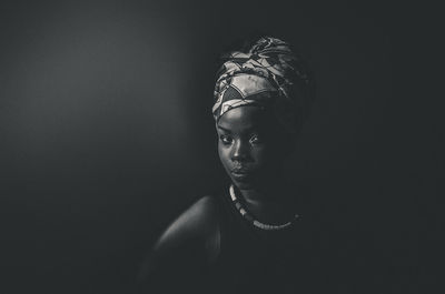 Portrait of young woman against black background