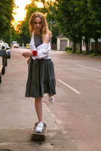 Full length portrait of smiling woman standing in park