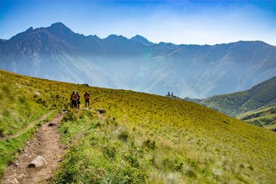 Rear view of people walking on mountain against sky