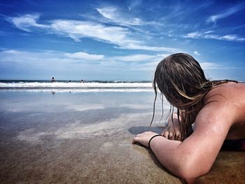 Shirtless woman lying on sand at daytona beach