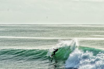 Man surfing in sea against sky