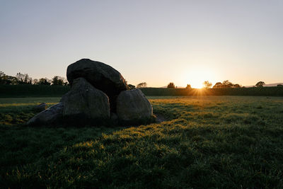 Scenic view of rocks on field against sky during sunset
