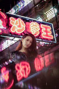 Portrait of young woman standing against illuminated text