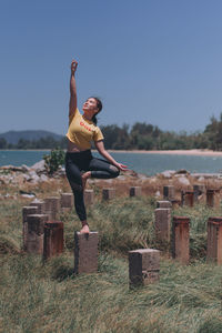 Full length of young woman standing by sea against clear sky