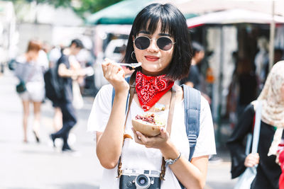 Portrait of young woman having snack on city street in city