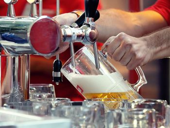 Close-up of man pouring beer in glass