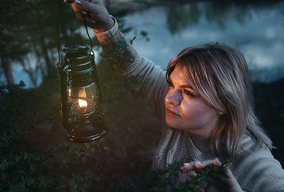 Portrait of young woman holding illuminated lighting equipment