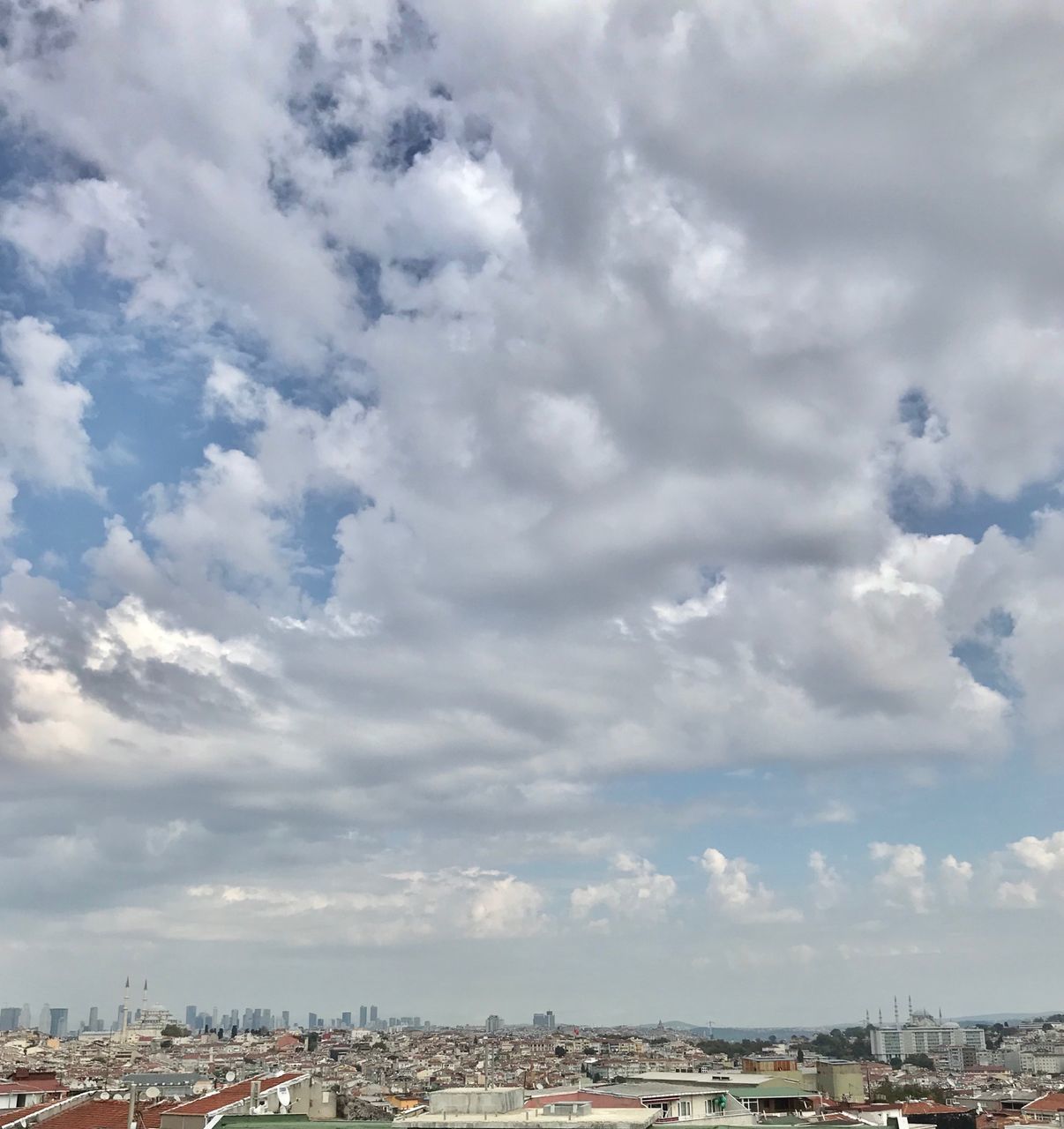 HIGH ANGLE VIEW OF BUILDINGS IN CITY AGAINST CLOUDY SKY