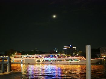 Illuminated bridge over river against sky at night