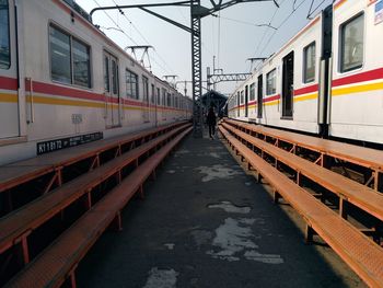 Rear view of woman walking amidst trains at railroad station platform